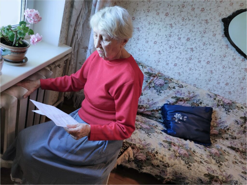 Elderly lady looking worried about energy bills whilst holding the radiator.