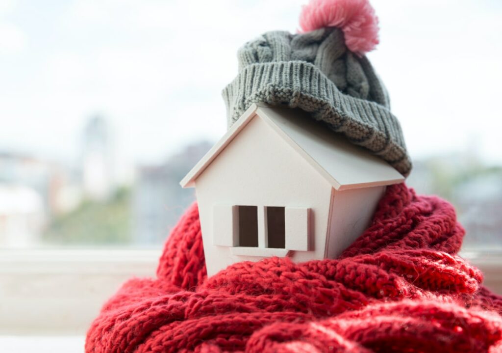 toy house wrapped up in a red scarf and grey hat to keep the warmth in.