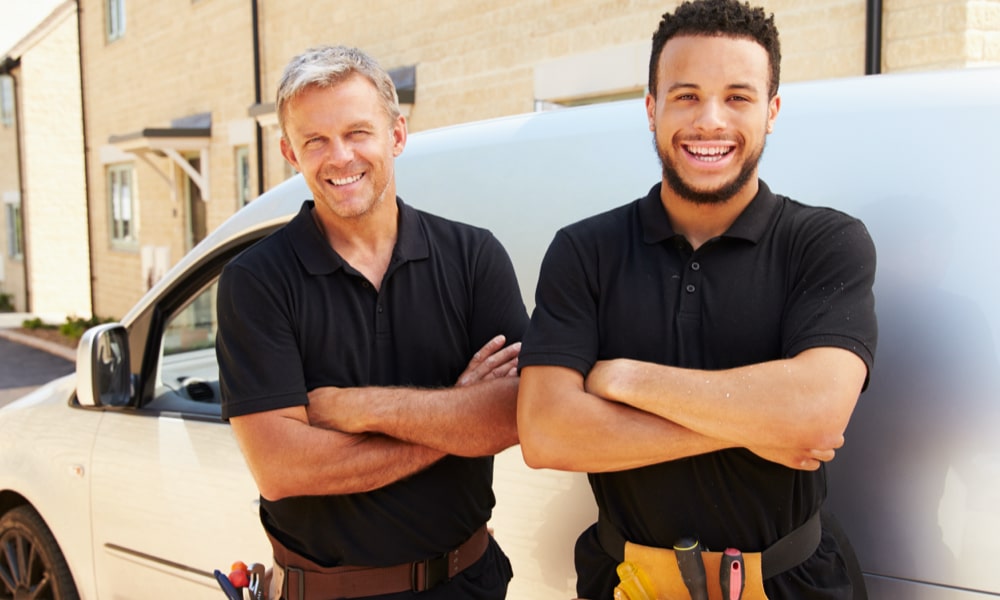 2 male insulation installers with arms folded smiling stood in front of their work van