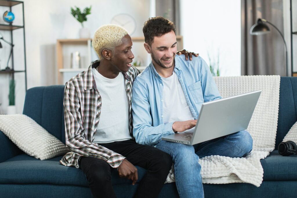 two people sat on a sofa looking at a laptop